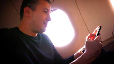 A man using a smartphone on a plane