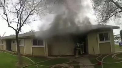 House with smoke billowing out and a fire fighter exiting