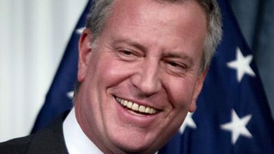 New York City Mayor Bill de Blasio smiles during a news conference to announce a tentative contract agreement with the Uniformed Superior Officers Coalition at City Hall in New York, December 9, 2014