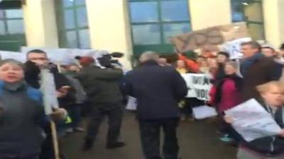 Councillors walk past protesters into meeting