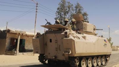 FILE PICTURE : Egyptian Army soldiers patrol in an armoured vehicle backed by a helicopter gunship during a sweep through villages in Sheikh Zuweyid, north Sinai, Egypt