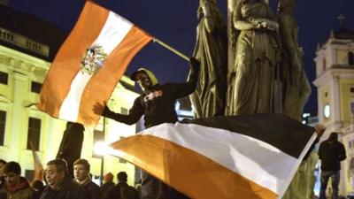Demonstrators wave flags and show banners during a rally of the group Pegida