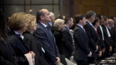 Members of the delegations of Croatia, left, and Serbia, right, stand up as judges enter the World Court in The Hague, Netherlands