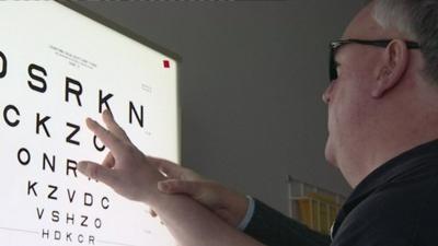 Man with macular degeneration looks at board with letters