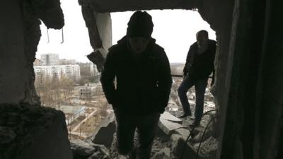 Municipal officials tour a residential block in Donetsk to assess the damage caused by what locals said was a shelling