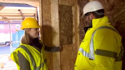 Craig White shows BBC science and environment reporter Victoria Gill the straw bale construction in the walls of the new homes