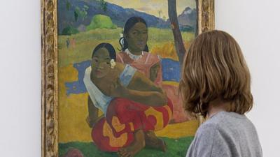 A woman looks at the painting "Nafea faa ipoipo"