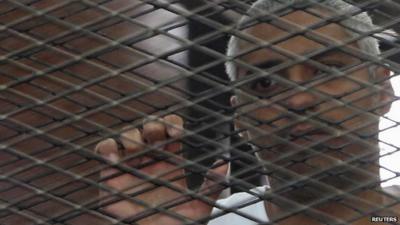 File picture of imprisoned al-Jazeera journalist Mohamed Fahmy behind bars in a Cairo courtroom during his initial trial