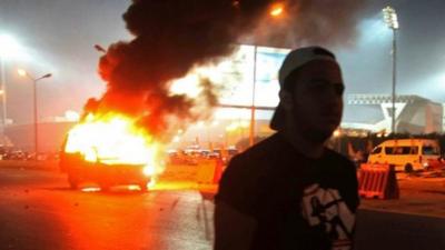 A football fan near a burning police car