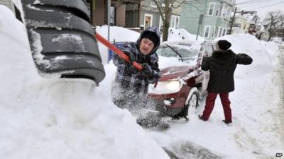 Couple shovelling snow from around car