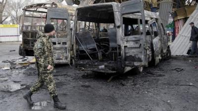 Pro-Russian rebels walk past damaged buses at a bus station in Donetsk, Ukraine,