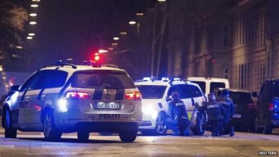 Police personnel and vehicles are seen along a street in central Copenhagen following shootings at a synagogue in Krystalgade