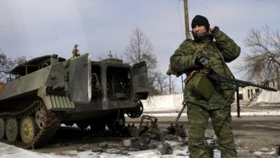 Pro-Russian separatist stands next to damaged military vehicle in the eastern Ukrainian city of Uglegorsk