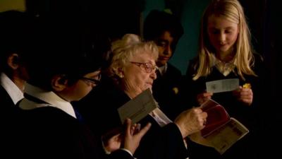 Children look at old ration books with Gladys