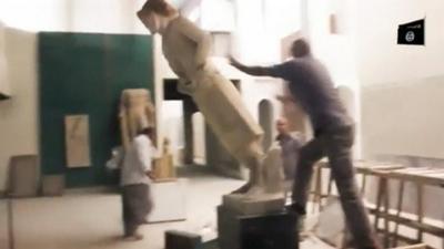A man pushes a statue off its plinth in a museum at a location said to be Mosul in this still image taken from an undated video