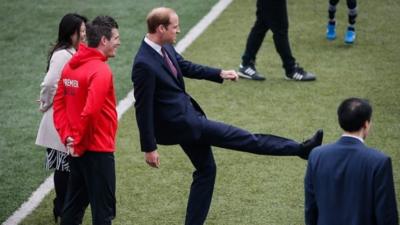 Prince William kicks a football in China