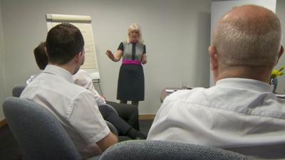 Kathryn Colas, consultant, speaking to group of men in office