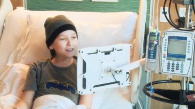 A boy using a computer touch screen in hospital