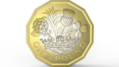 The new pound coin. It has twelve edges, with an outer golden ring and an inner silver ring. The design on the front shows a leek, thistle, shamrock and rose coming out of a crown.