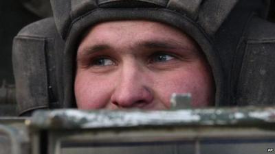 Close up of Ukrainian soldier's face as he looks over top of military vehicle