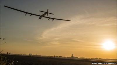 File photo of Solar Impulse flying in the sky as the sun sets to the right of it