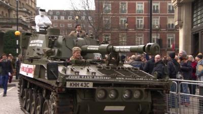 A tank with a man dressed as Stig on it