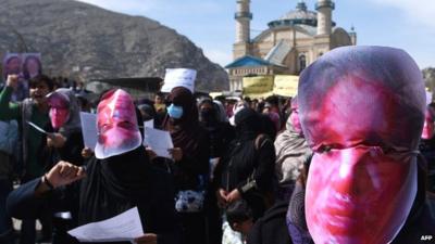 Afghan members of the Solidarity Party of Afghanistan wearing masks bearing an impression of Farkhunda's bloodied face protest against the attack in Kabul