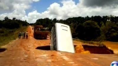 A bus falls into a hole in the road
