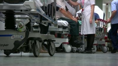 Queue of beds in A&E with patients and nursing staff