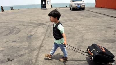 Chinese boy, evacuated from conflict in Yemen, pulling suitcase across port in Djibouti