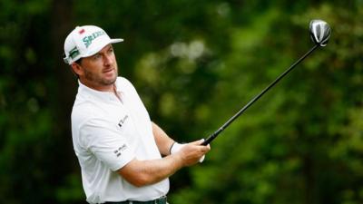 McDowell watches his tee shot at the second hole on Friday