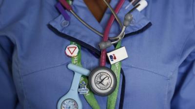 Detail of nurse wearing a watch and stethoscope around her neck