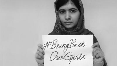 Malala Yousafzai holds up a sign saying Bring Back Our Girls