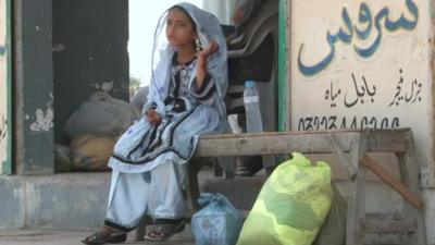 Young girl in Gwadar, Pakistan sitting outside a shop