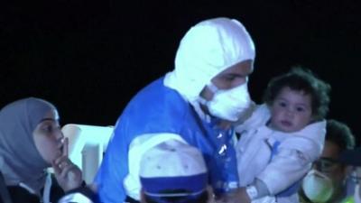 A child and mother are rescued from a migrant boat in Sicily