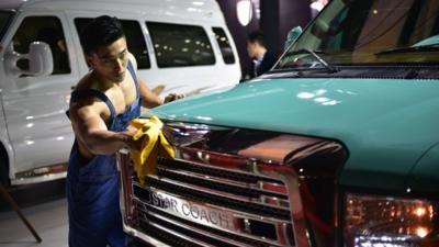 A model cleans a car of Chinese company Star Coach at the 16th Shanghai International Automobile Industry Exhibition in Shanghai