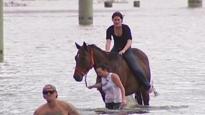 A woman riding a horse through flood water