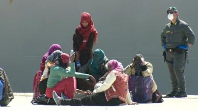 Migrants sit on quay