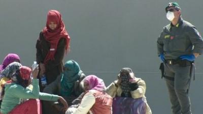 Migrants sit on quay