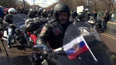 Bikers, one with a Russian flag on his bike
