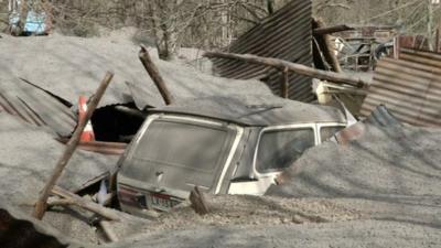 A car buried in the midst of ash and wreckage