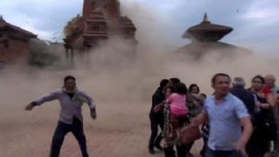 Still from footage of people running as temple collapses