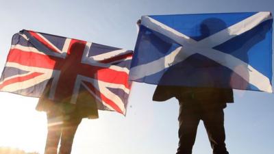 Scottish and English flags held up over Edinburgh, Scotland