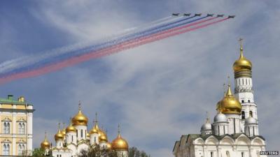 Six planes trailing white, blue and red fly over Moscow during Victory Day celebrations