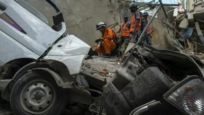 Workers picking through wreckage and rubble