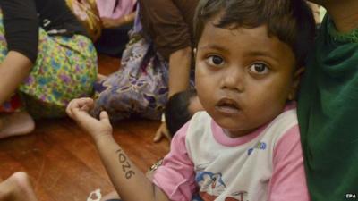 Close up of a migrant girl from Myanmar in the arms of her mother in Malaysia