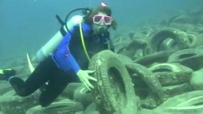 Diver holds up tyre under water