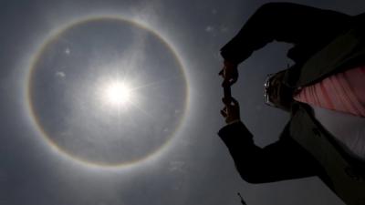 A man takes a photo of a solar halo in Mexico City