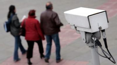 People walk past CCTV camera