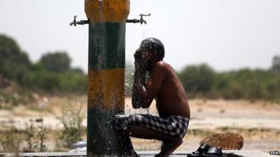 An Indian labourer cools off under a water tap on a hot afternoon in Amritsar, India